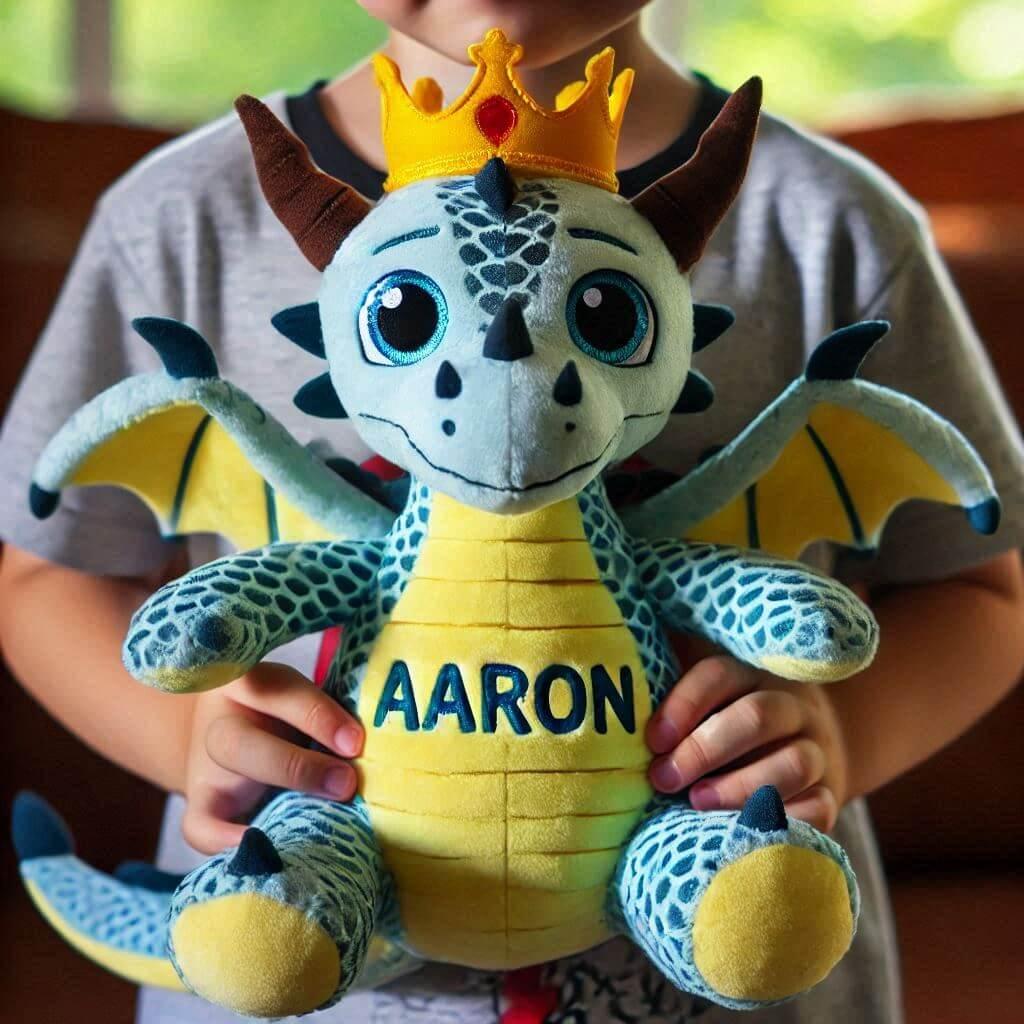 Le prenom aaron ecrit sur une peluche dragon avec une couronne dans les bras dun petit garcon 1