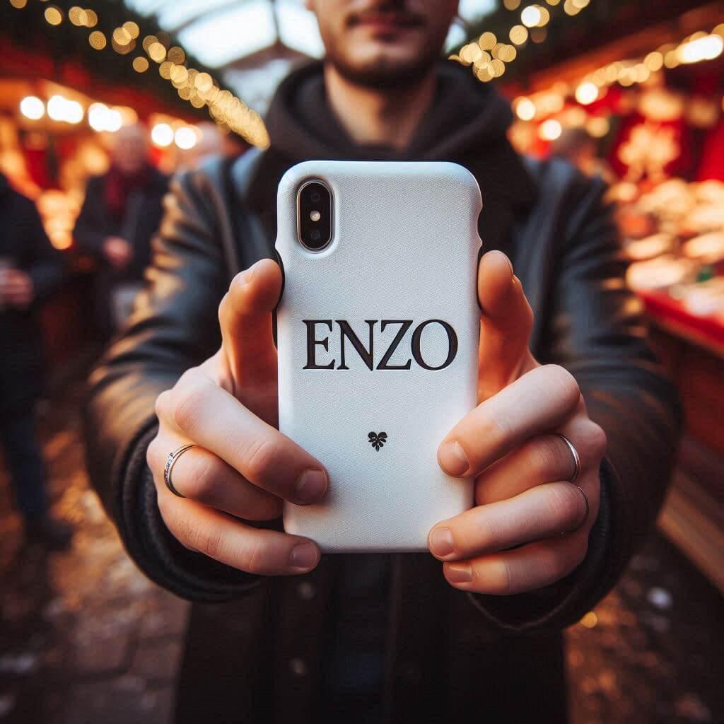 Le prenom enzo ecrit sur une coque de telephone tenu dans les mains dun homme au marche de noel 1