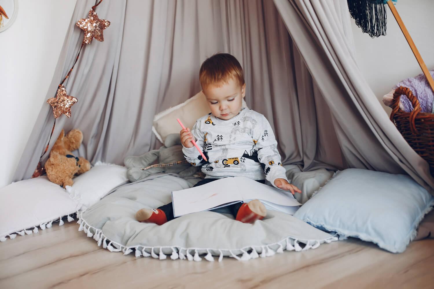 Petit bebe qui est en train de lire dans sa chambre montessori