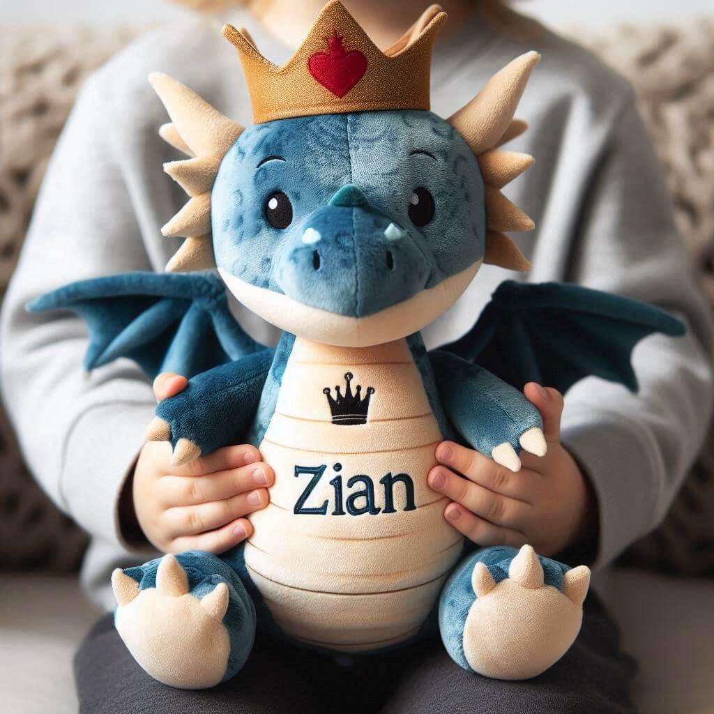 Une peluche dragon avec une couronne personnalisee avec le prenom zian dans les mains dun petit garcon