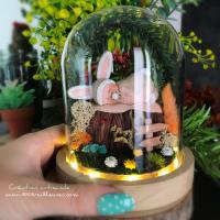 Gorgeous handmade night light illuminated in the form of a glass dome with a miniature rabbit-themed garden, presented next to a hand